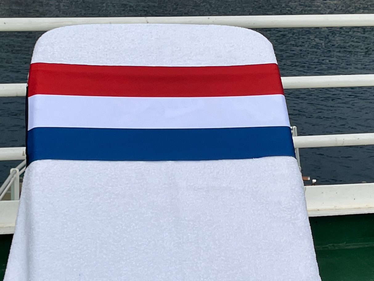 The National flag of the Netherlands holding a towel onto a sun Lounger. See tcboo.shop